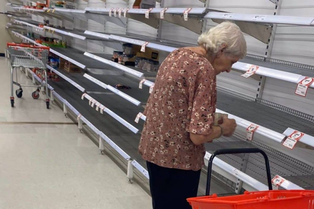 Idosa chorando em meio às prateleiras vazias de um supermercado na Austrália