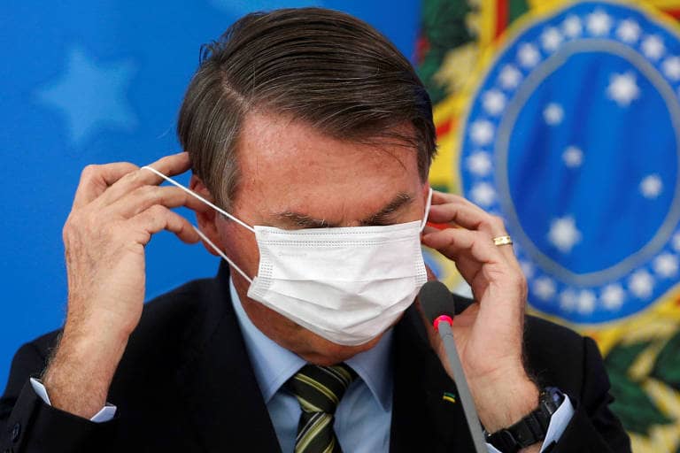 Bolsonaro tentando colocar máscara do jeito certo mas não conseguindo