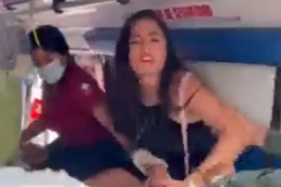 Imagem da namorada ciumenta sendo retirada de dentro da ambulância por um socorrista.