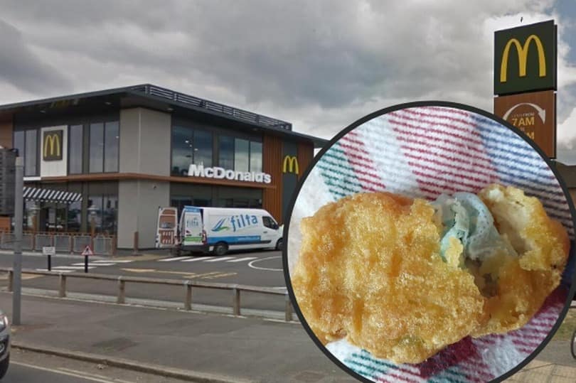 Foto de fundo de um restaurante do McDonalds com uma ambulância na porta da loja. A frente da imagem em uma montagem, um círculo mostrando o pedaço de máscara dentro do nugget