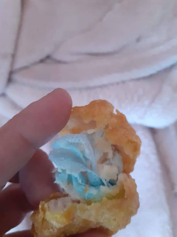 Mão da mãe da criança segurando o nugget com pedaço da máscara azul